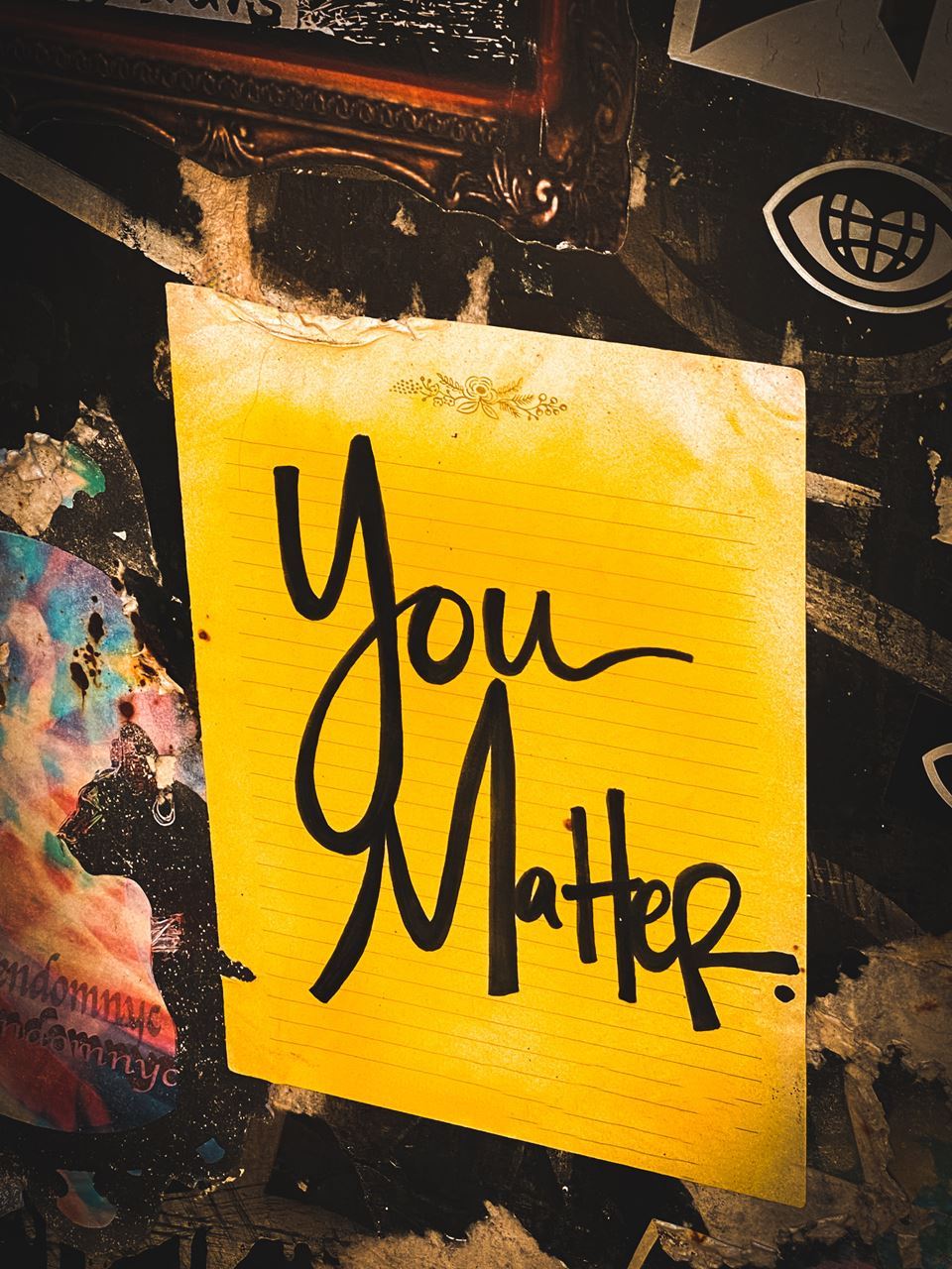 The text "You Matter" written on a sheet of yellow notebook paper, against a graffiti-style background