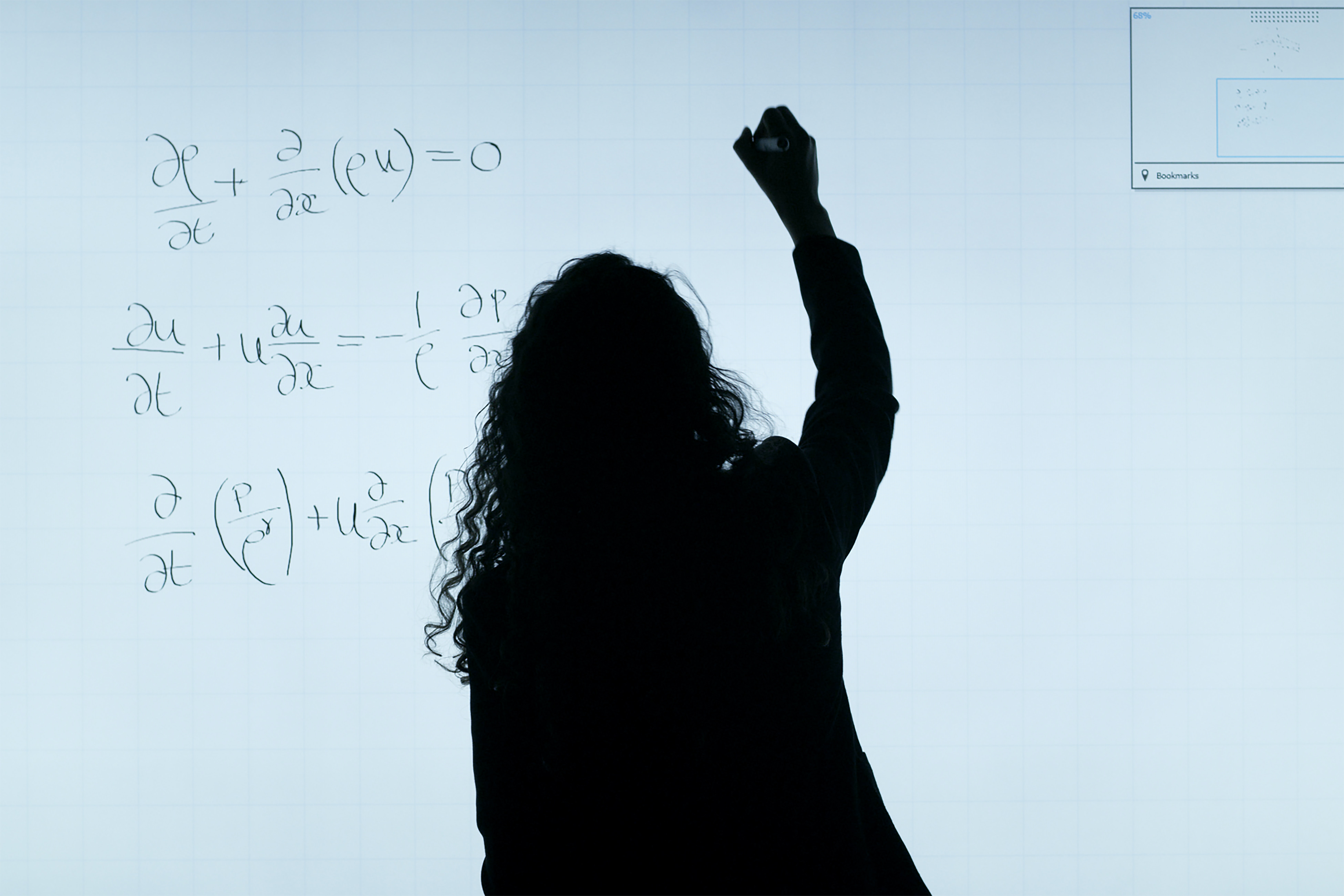 A silhouette of a person writing equations on a whiteboard